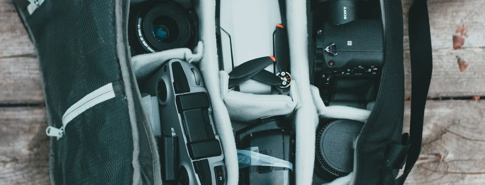 Top-down view of camera bodies, lenses and accessories organised inside a padded camera bag.